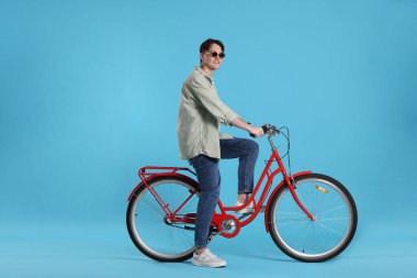 Açık mavi arka planda kırmızı bisiklete binen yakışıklı adam, metin için boşluk