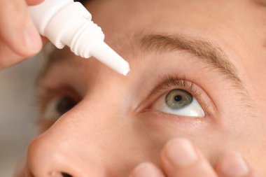 Işık arkaplanına göz damlası uygulayan adam, yakın plan