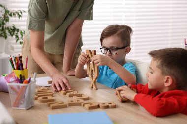 İlkokulda ahşap masada öğretmenden ders alan küçük çocuklar, yakın çekim.
