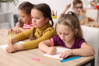 İlkokulda ahşap masada ders alan çocuklar, yakın çekim.