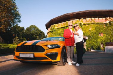 Modern Cabriolet yakınlarında güneş gözlüklü şık bir çift, düşük açılı.