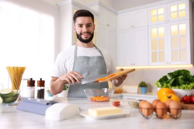 Mutfaktaki masada yemek pişiren gülümseyen adam.
