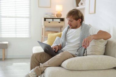 Evdeki kanepede dizüstü bilgisayar kullanan adam, mesaj için yer