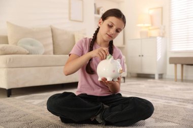 Küçük kız evdeki domuz kumbarasına para yatırıyor. Cep harçlığı ve sorumluluk