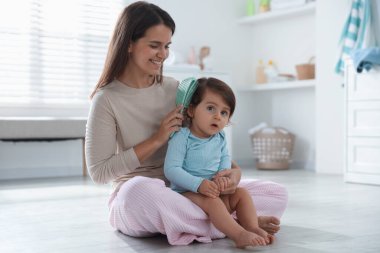 Anne banyoda bebeğinin saçını tarıyor.