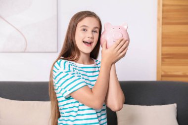 Cep harçlığı. Evdeki kanepede kumbaralı kız.