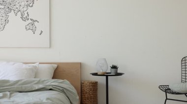 Yan masalar, sandalye ve yatak odasındaki beyaz duvarın yanında rahat geniş yatak, sola hareket eden kamera.