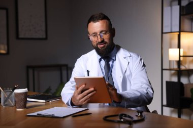 Doktor, gece vardiyası sırasında klinikte tablet üzerinde çalışıyor.