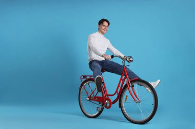 Açık mavi arka planda kırmızı bisiklete binen yakışıklı adam, metin için boşluk