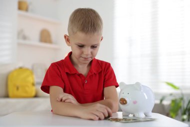 Cep harçlığı ve kumbarası olan küçük bir çocuk.