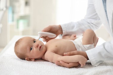 Pediyatrist bebeğin sıcaklığını hastanede termometreyle ölçüyor, yakın plan. Metin için boşluk