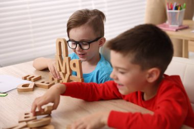İlkokulda ahşap masada ders alan küçük çocuklar, yakın çekim.