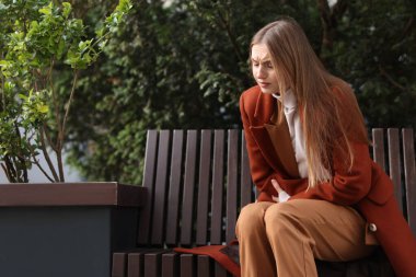 Genç bir kadın mide ağrısı ve mide bulantısı çekiyor açık havada, mesaj için yer var.