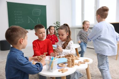 İlkokulda ders sırasında beyaz masalarda oturan sevimli çocuklar.