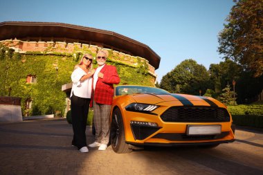 Modern Cabriolet yakınlarında güneş gözlüklü şık bir çift, düşük açılı.