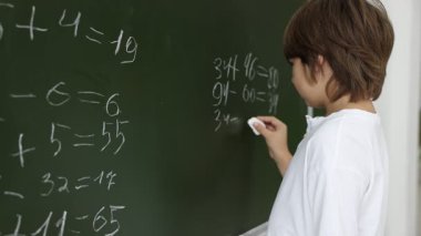 Okula dönelim. Çocuk içeride karatahtayla matematik yapıyor.