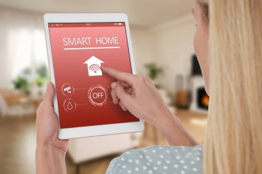 Tablet bilgisayarda ev özelliklerini kontrol etmek için akıllı ev uygulaması kullanan kadın, kapat