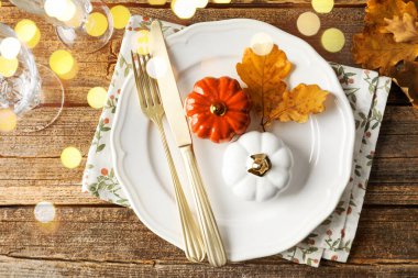 Sonbahar masası ayarı, Bokeh ışıkları. Tabak, çatal bıçak, dekor ve gözlükler ahşap masa, üst manzara