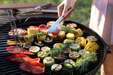 Vejetaryen barbeküsü. Dışarıdaki ızgarada sebze pişiren kadın, yakın plan.