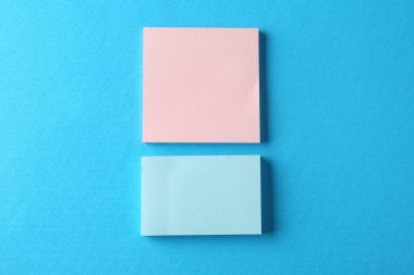 Açık mavi arkaplandaki boş renkli notlar, üst görünüm. Metin için boşluk