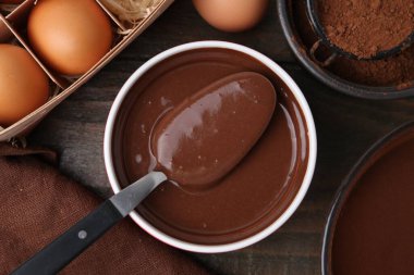 Kase içinde sıvı çikolata hamuru ve ahşap masa üzerinde malzemeler, düz yatıyordu.