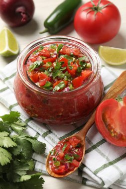 Kavanozda lezzetli salsa ve beyaz masada malzemeler, yakın plan.