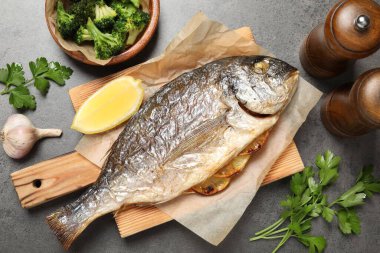 Lezzetli ızgara balık, brokoli ve baharat gri masada.