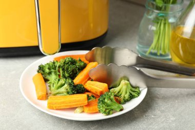 Lezzetli ızgara sebzeler, maşalar ve tava gri masada, yakın plan.