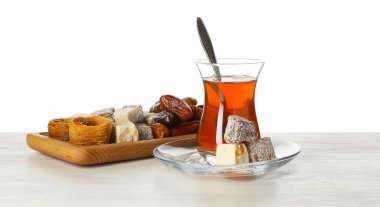Geleneksel Türk çayı ve tatlıları beyaz arka plana karşı ahşap masada