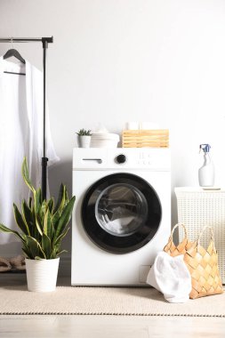 Çamaşırhanedeki çamaşır, deterjan ve çiçekli çamaşır makinesi. İç tasarım