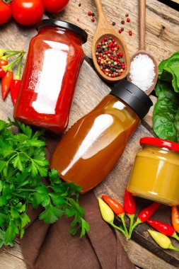 Farklı lezzetli soslar ve sebzeler ahşap masada, düz yerde.