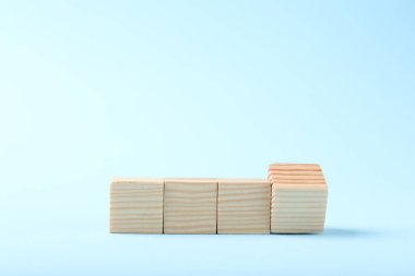 Blank wooden cubes on light blue background, space for text
