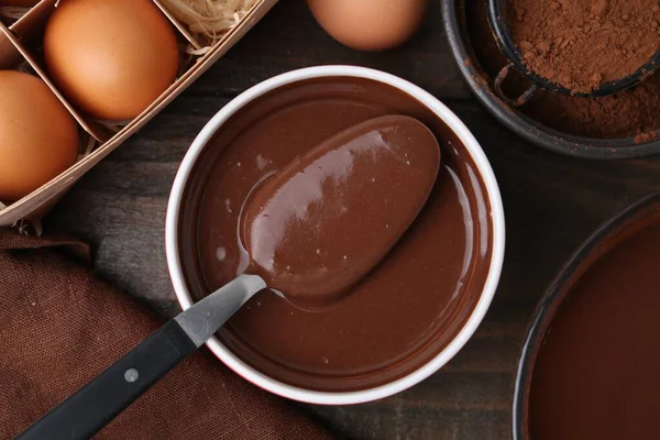 Kase içinde sıvı çikolata hamuru ve ahşap masa üzerinde malzemeler, düz yatıyordu.