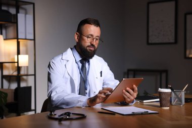 Doktor, gece vardiyası sırasında klinikte tablet üzerinde çalışıyor.