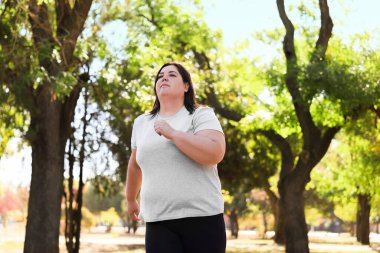 Parkta koşan şişman bir kadın, düşük açılı bir manzara. Sağlıklı yaşam tarzı