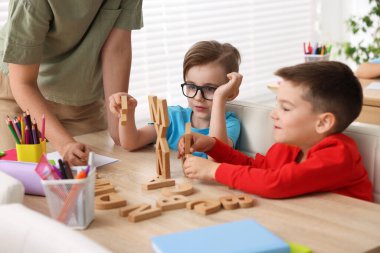İlkokulda ahşap masada öğretmenden ders alan küçük çocuklar, yakın çekim.