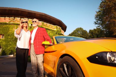 Modern Cabriolet yakınlarında güneş gözlüklü şık bir çift, düşük açılı.