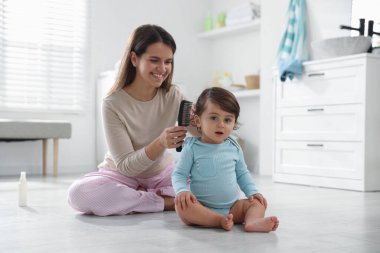 Anne banyoda bebeğinin saçını tarıyor.