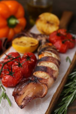 Lezzetli kalamar, biberiye ve domatesler ahşap masada, yakın plan.