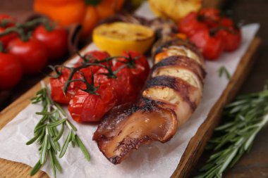 Lezzetli kalamar, biberiye ve domatesler ahşap masada, yakın plan.