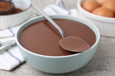 Gri masadaki kasede sıvı çikolata hamuru, yakın plan.