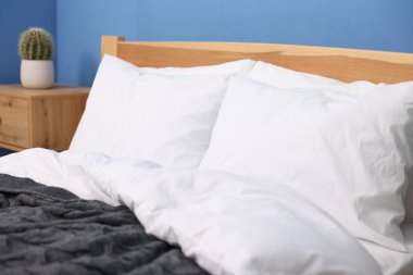 Mavi duvarın yanında sıcak, temiz çarşafları olan bir yatak, yakın plan.