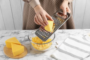 Beyaz mermer masada peynir rendeliyor, yakın plan.