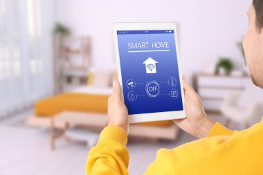 Tablet bilgisayarda ev özelliklerini kontrol etmek için akıllı ev uygulaması kullanan adam, kapat