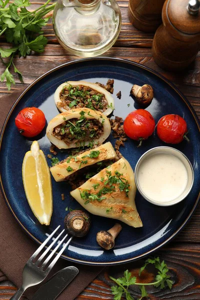 Mantarlı, maydanozlu, domatesli ve soslu ahşap masada servis edilen lezzetli ızgara kalamar parçaları.