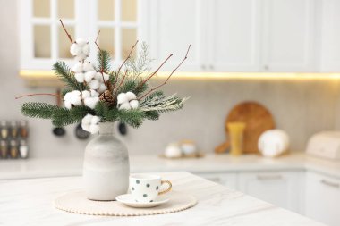 Vazoda köknar ağacı dalları ve kapalı alanda beyaz mermer masa üzerinde çay fincanı ile güzel bir kompozisyon, yazı için yer. Kış Dekorasyonu