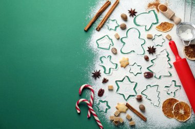 Yeşil arka planda kurabiye pişirmek için şeker kamışları, malzemeler ve çatal bıçaklar, metin için yeri olan düz yataklar. Noel sezonu