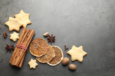 Gri masa üzerinde kurabiyeler ve baharatlarla Noel kompozisyonu. Metin için boşluk