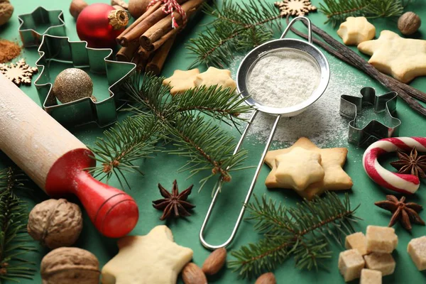 Yıldızlar, kesiciler, köknar ağacı dalları ve yeşil arka planda baharatlar şeklinde kurabiyeler içeren Noel kompozisyonu, yakın plan