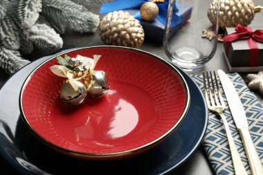 Tabaklar, çatal bıçak takımı ve gri masa üzerindeki şenlikli Noel dekoru, yakın plan.